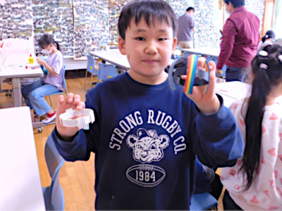 完成したブレスレットをカメラに見せている男の子
