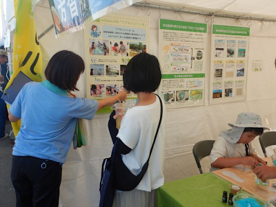 展示されているポスターの説明を受ける女性
