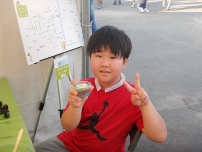 作成した芳香剤を持ちこちらにピースを向ける少年