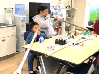 作成した紙筒の楽器を親子で楽しむ様子