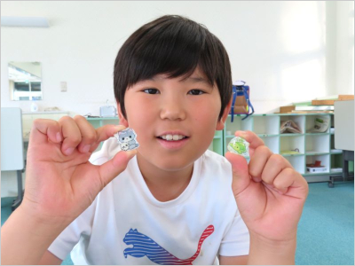 完成した作品を両手でカメラに見せている男の子の様子