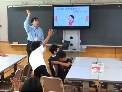 説明している職員と、元気に手を挙げて発言しようとしている男の子の様子