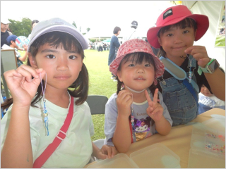 完成したアクセサリーをカメラに見せてくれる3人の女の子の写真