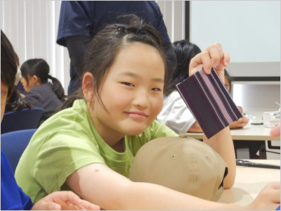 作品をカメラに見せている、女の子の写真