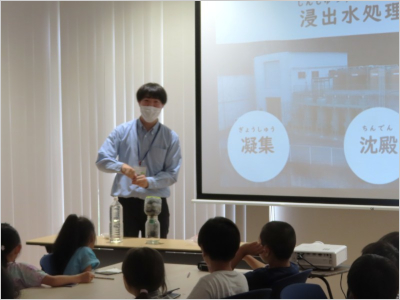 スクリーンの前で子供たちに説明している職員の様子