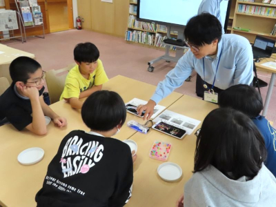 材料を指差しながら説明するスタッフの様子