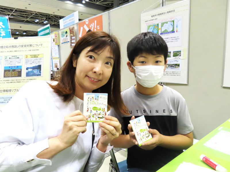 作成したメモ帳を手に、カメラに笑顔を向けている親子